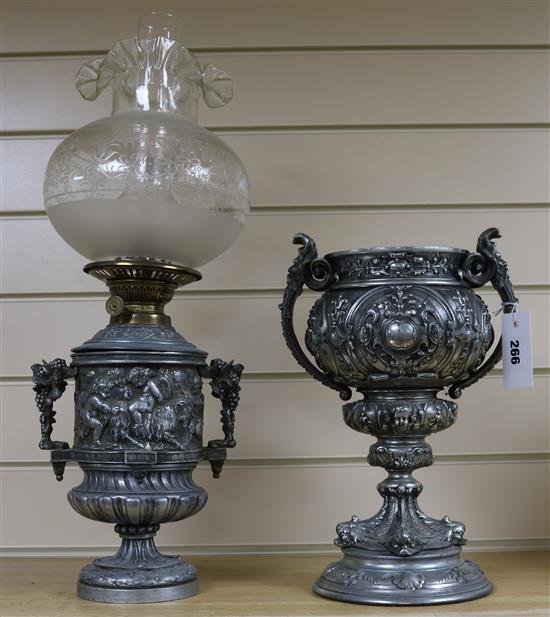 A 19th century silvered metal two handled vase and an oil lamp cast with bacchanalians, (2)